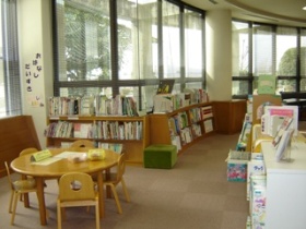 図書室書架と低いテーブルと小さい椅子の閲覧席の画像